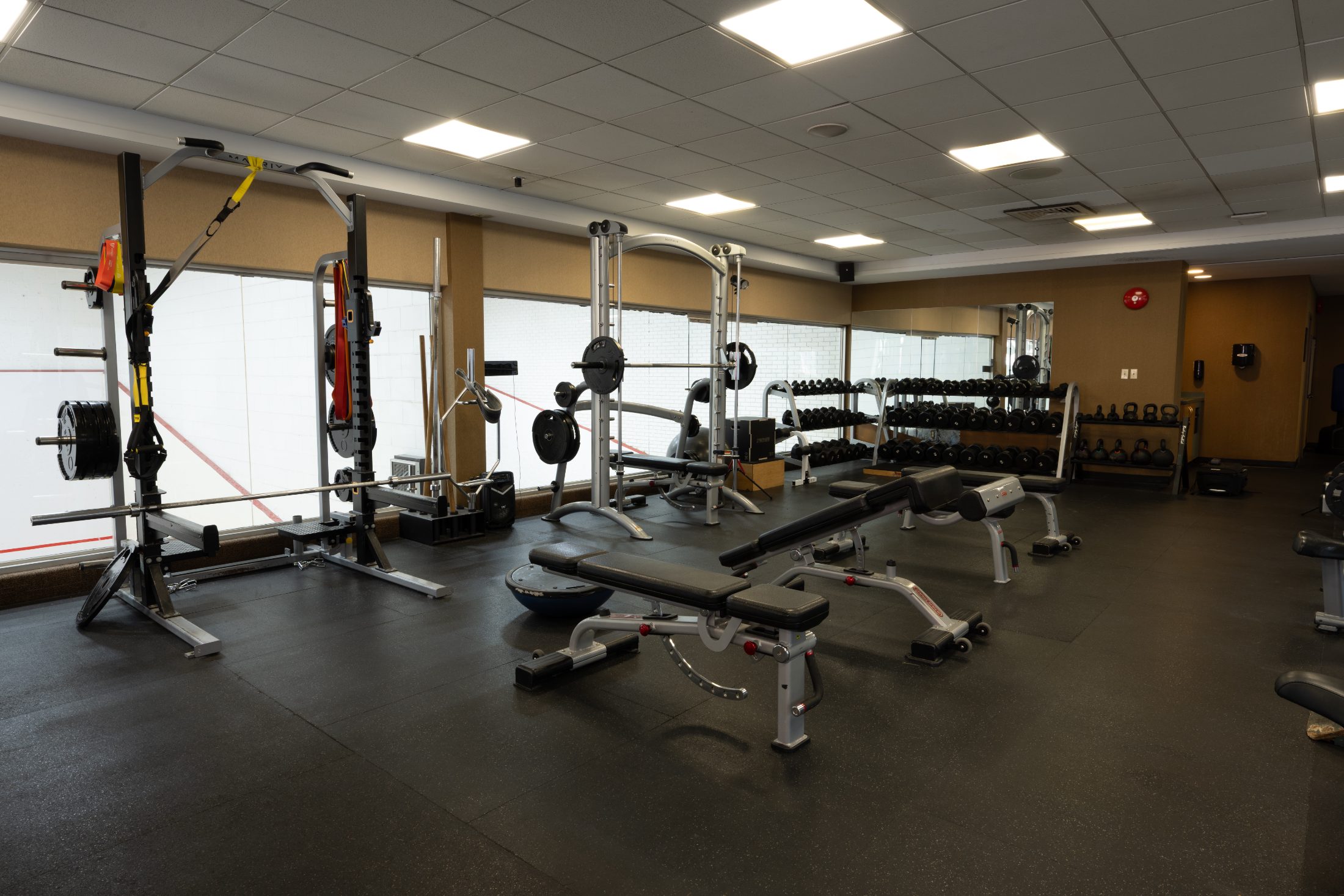 Racks and dumbbells beside the court glass